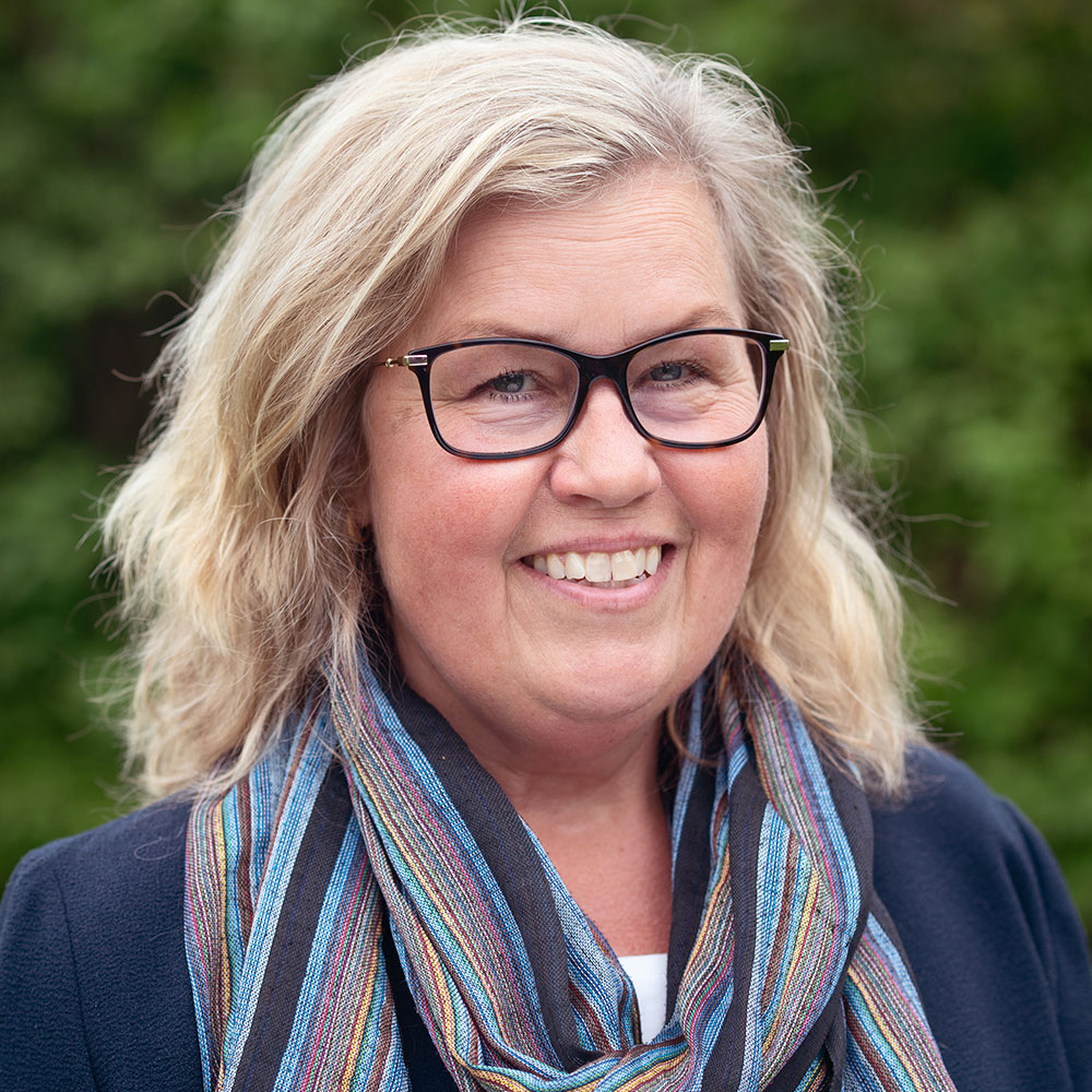 Kvinna med blont hår och glasögon. Blå kavaj och blårandig scarves - Maria Stålgren.